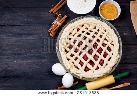 Raw Cherry Pie In A Glass Round Form And Ingredients For Making Cake  - Flour, Egg, Cherry, Brown Su