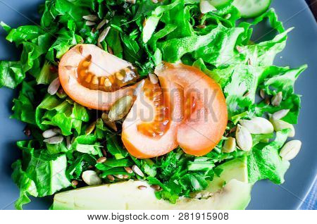 Fresh  Green Salad With Cucumber, Lettuce, Avocado And Tomatoes And Glass Water On A White Wooden Ta