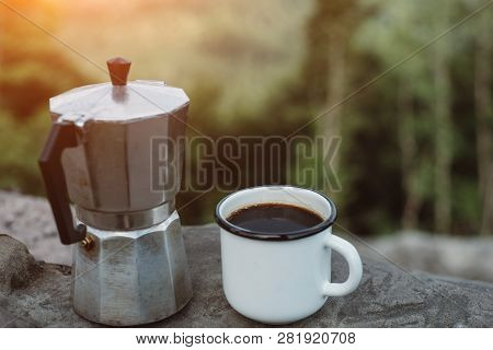 Cup Hot Coffee And Coffee Maker On Background Of Nature During The Sunset . Concept Adventure Active