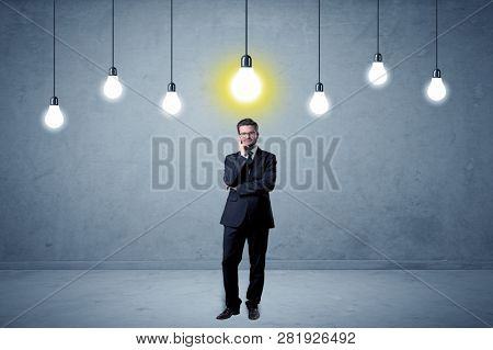 Handsome businessman in an empty space with bulbs above and uninspired face