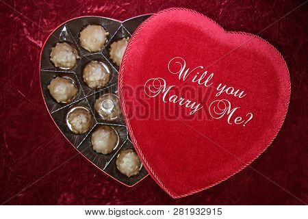 Valentines Day. Wedding Ring or Engagement Ring with Chocolates in a Red Velvet Valentines Day Heart Shaped Box. Marriage Proposal. Will you Marry Me?. Room for text. 
