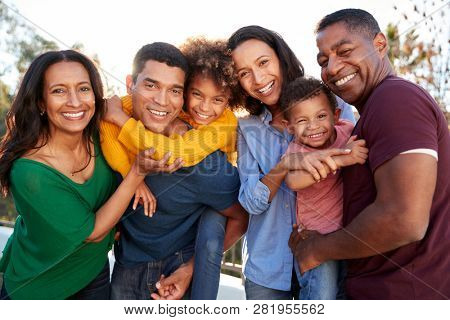 Mixed race three generation family playing together in the garden, smiling to camera