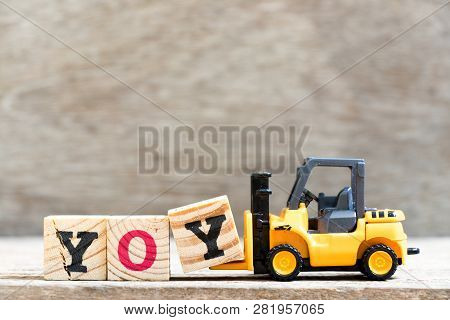 Toy Forklift Hold Letter Block  In Word Yoy (abbreviation Of Year Over Year) On Wood Background