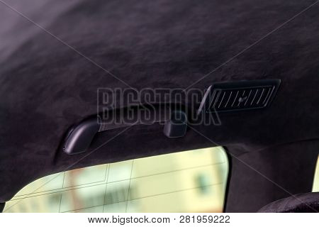 A Close-up View Of A Black Plastic Handle On The Ceiling In A Car In A Passenger Seat Pulled By A Bl