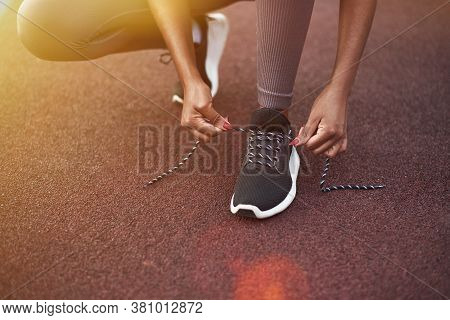 Black Girl Laces Up Her Sneakers While Doing Sports On The Street. Outdoor Fitness Concept.