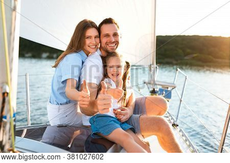 Family Gesturing Thumbs-up Relaxing On Yacht Posing Sitting On Deck Enjoying Sailing In Sea On Summe