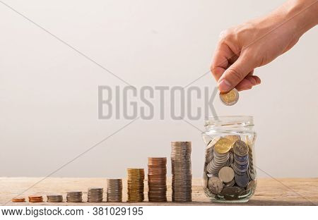 White Hand Man Holding Gold Coin To Putting In Jar Or Glass Bottle For Saving With Soft White Backgr