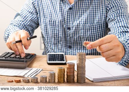 Business Man Hand Holding Or Putting Coins On Stack Coin, Another Hand Use Poin To Calculator.saving