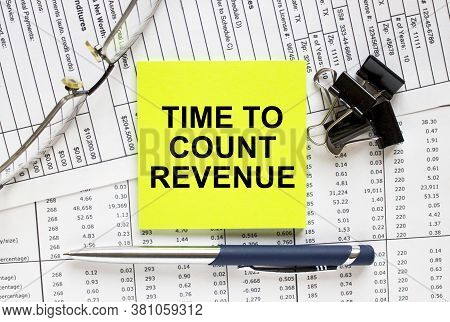 Text Time To Count Revenue On Financial Tables With Pen, Glasses And Paper Clips
