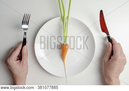 Woman Holding Fork And Kinfe, Ready To Eat. Diet Concept. One Carrot On The Plate On Whte Table.