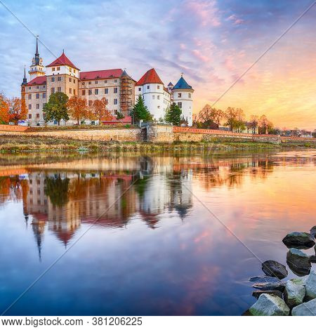 Fantastic Morning View Of Hartenfels Castle On Banks Of The Elbe. Dramatic Sunrise. Location: Torgau