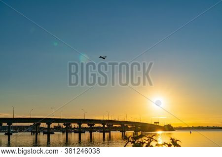 Sweeping Lines Of Tauranga Harbour Bridge Over Calm Blue Water With Glow Of Rising Sun At Far End As