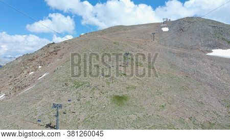 Cableway On Mountaintop In Cloudy Weather. Modern Ropeway With Benches In Amazing Mountainous Terrai