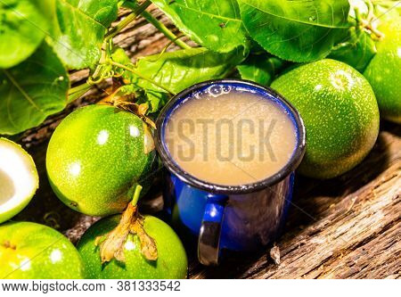 Passion Fruit Juice Served In A Blue Metal Mug And Fresh Fruits Around It
