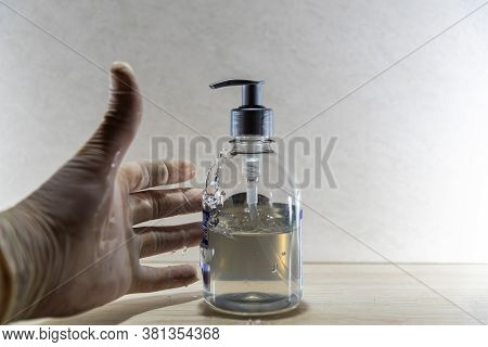 Human Hand With Disposable Glove In Motion To Hold Alcohol Gel In Covid 19 Prevention