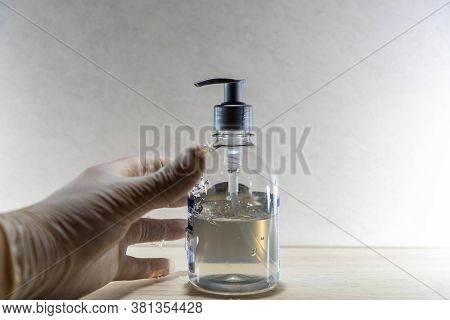 Human Hand With Disposable Glove In Motion To Hold Alcohol Gel In Covid 19 Prevention