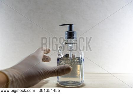 Human Hand With Disposable Glove In Motion To Hold Alcohol Gel In Covid 19 Prevention