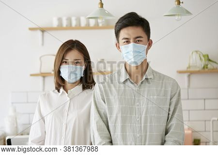 Portrait Of A Young Asian Couple Wearing Mask Looking At Camera