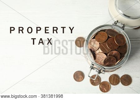 Text Property Tax Near Jar Full Of Coins On White Wooden Table, Top View