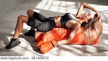 Very Pretty And Attractive Sportswoman Posing In A Light Studio Lying On The Floor With A Large Oran