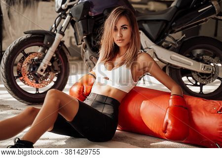 Hot And Attractive Looking Sportswoman Posing In A Light Studio Sitting On The Floor With A Large Or
