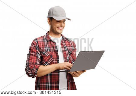 Young man with a cap and a checkered shirt working on a laptop computer isolated on white background