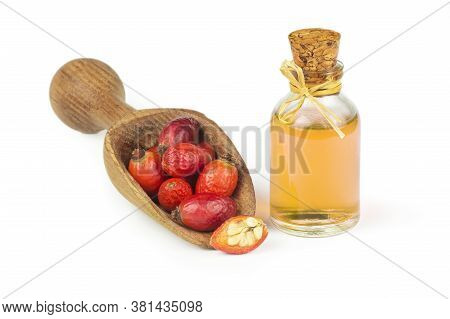 Glass Bottle Of Rosehip Seed Essential Oil With Fresh Rose Hip Fruits Isolated On White Background. 