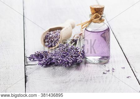 Glass Bottle Of Lavender Essential Oil With Fresh Lavender Flowers And Dried Lavender Seeds On White