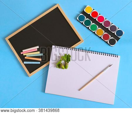Back To School. Watercolors With White Notebook And Brush On Blue Background. Black School Chart And