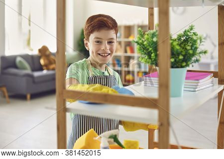 Adorable Little Boy In Rubber Gloves Cleaning Shelf With Rag At Home. Cute Kid Helping To Do Domesti