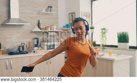 Joyful Wife Singing On Wooden Spoon While Listening Music On Headphones In The Morning. Energetic, P