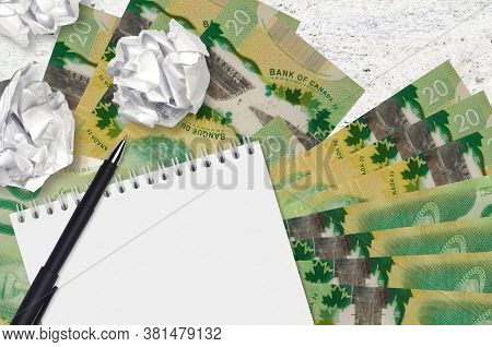 20 Canadian Dollars Bills And Balls Of Crumpled Paper With Blank Notepad. Bad Ideas Or Less Of Inspi