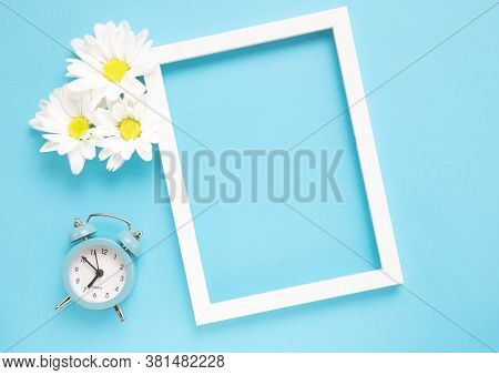 Square White Frame With White Flowers And Blue Alarm Click On Blue Background. View Top. Check Up Ti