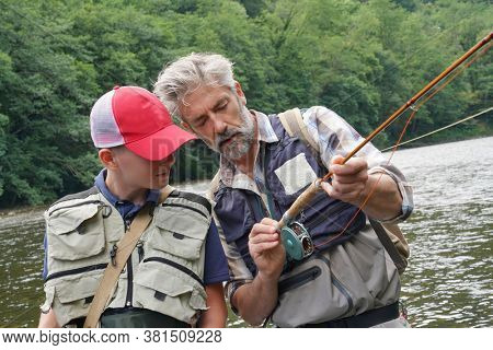 A father and his son fly fishing in summer on a beautiful trout river with clear water