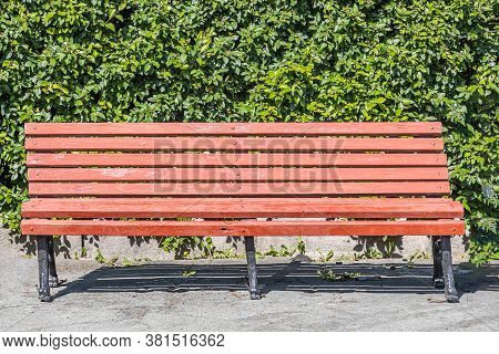 Old Wooden Painted Brown Color Beautiful Bench With Black Wrought-iron Legs Stands By The Walkway In