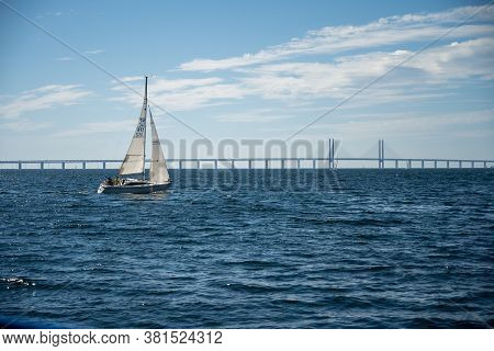 Malmo, Sweden - August 6, 2020: A Sailboat Sailing In Front Of The Oresund Bridge Linking Denmark Wi