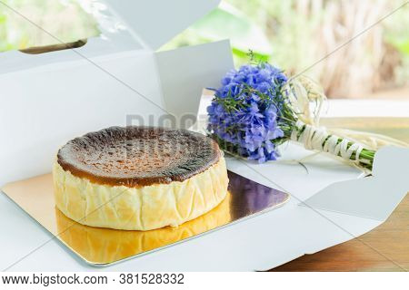 Basque Burnt Cheesecake With With Hydrange Bouquet On Wooden Table.