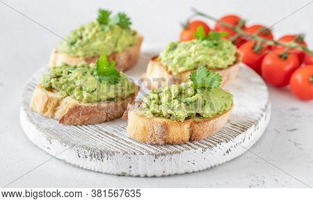 Avocado Toasts With Tomatoes On The Wooden Board