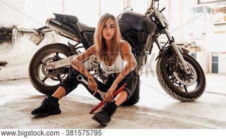 Super Sexy Young Girl With Wrenches Posing In A Photo Studio With A Sports Motorcycle