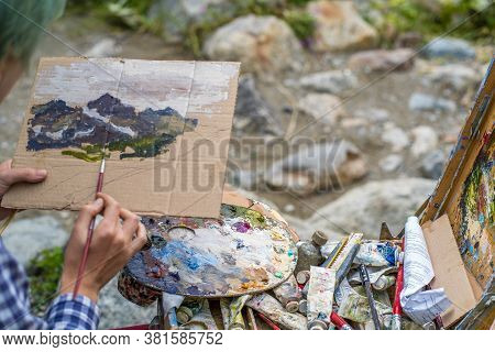 Dombay, Russia 26 July 2020: Close Up Of Young Woman Drawing Picture On Cardboard On Hike. Paintress