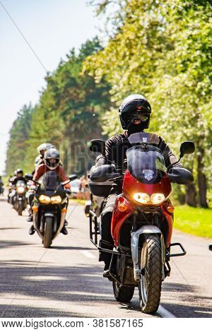 Motorcyclist Rides On The Road On A Sunny Summer Day. A Column Of Motorcycles Goes To A Motor Festiv