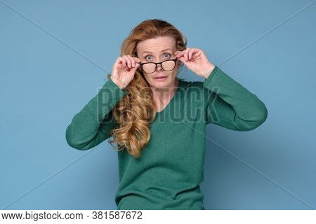 Caucasian Mature Woman Looks Scrupulously And Attentively Through Glasses