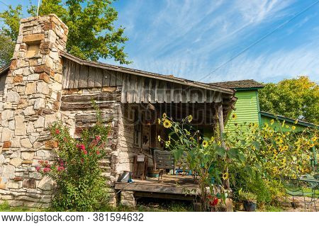 Carthage Usa - September 7 2015; Rustic Old Farm House With Stone Chimney And Sunflowers Growing Aro