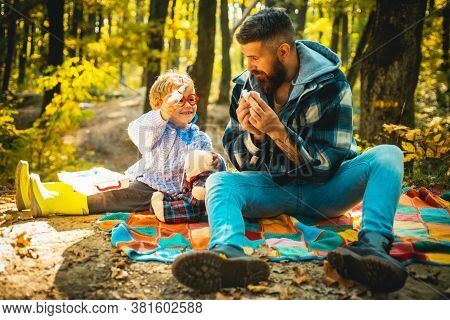 Child Makes A Cure For The Common Cold In Autumn Park. Father And Son Playing In The Autumn Forest. 