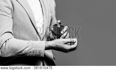 Man Holding Up Bottle Of Perfume. Men Perfume In The Hand On Suit Background. Man In Formal Suit, Bo
