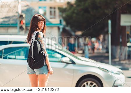 Close Up Portrait Of A Woman Stands Near A Road. In The Background, A Car Is Driving Along The Road 