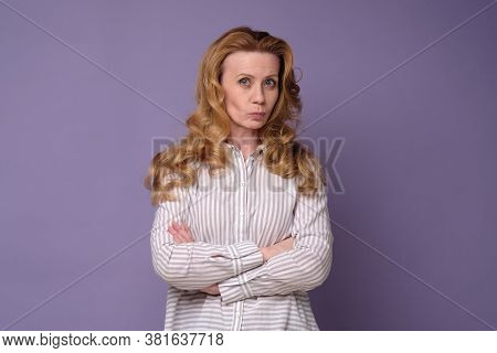 Serious Caucasian Woman With Folded Arms Isolated On A Colored Background.