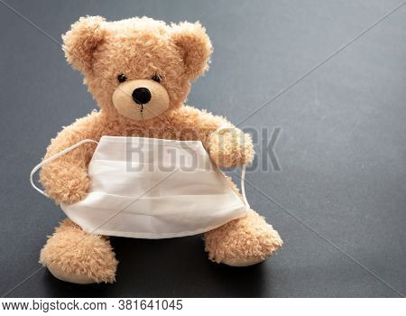 Coronavirus And Pollution Protection Concept. Teddy Bear With Protective Face Mask On Gray Backgroun