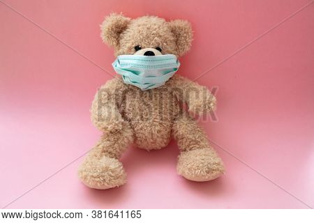 Coronavirus And Pollution Protection Concept. Teddy Bear With Protective Face Mask On Pink Backgroun