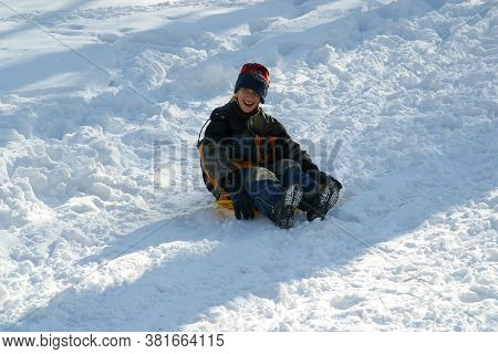 ZAGREB, CROATIA - JANUARY 12, 2014: Children sledding down the hill at winter time, Park Maksimir in Zagreb, Croatia